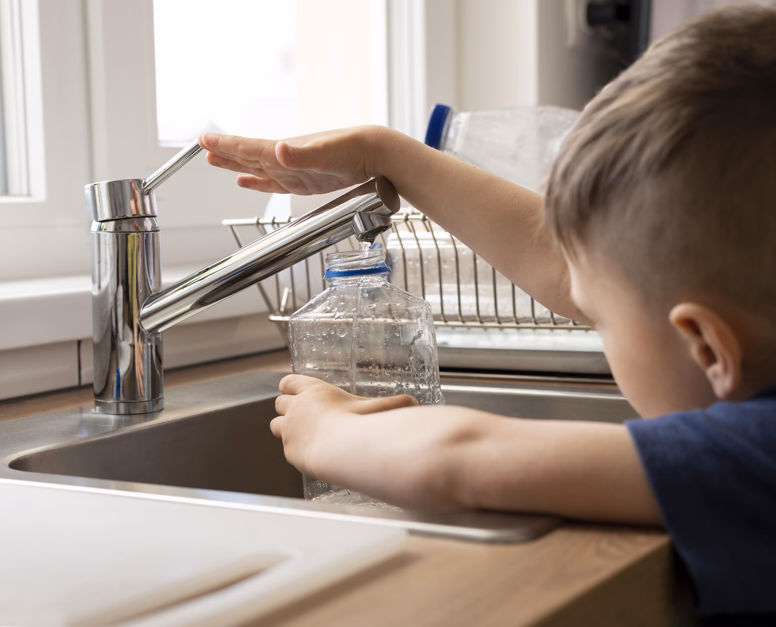Verre d'eau pure remplie au robinet d'une maison équipée d'un système anti-calcaire au CO₂, illustrant une eau saine et minéralisée