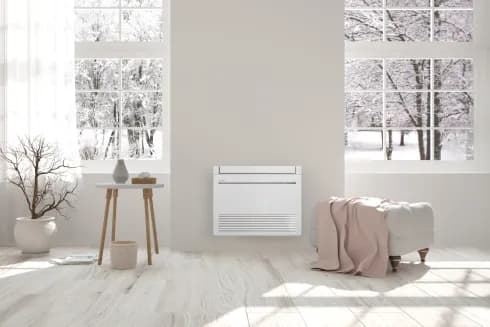 Console Mitsubishi Electric posée au sol dans un séjour lumineux : chauffage par le bas et rafraîchissement, installée par Kozéo