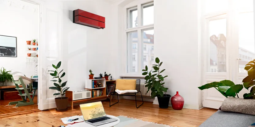 Climatiseur mural Mitsubishi Electric rouge rubis installé dans un salon lumineux au parquet bois