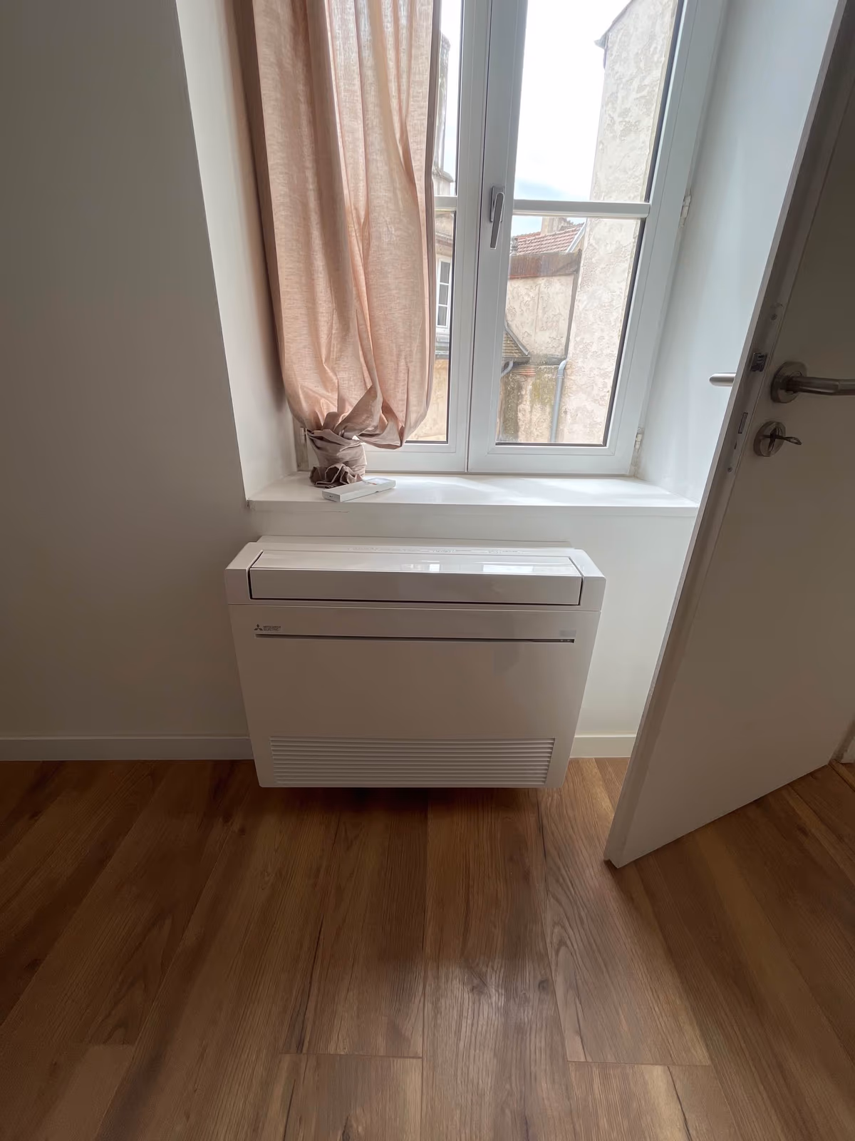 Climatisation réversible Mitsubishi en console au sol installée par Kozéo sous une fenêtre à Dijon