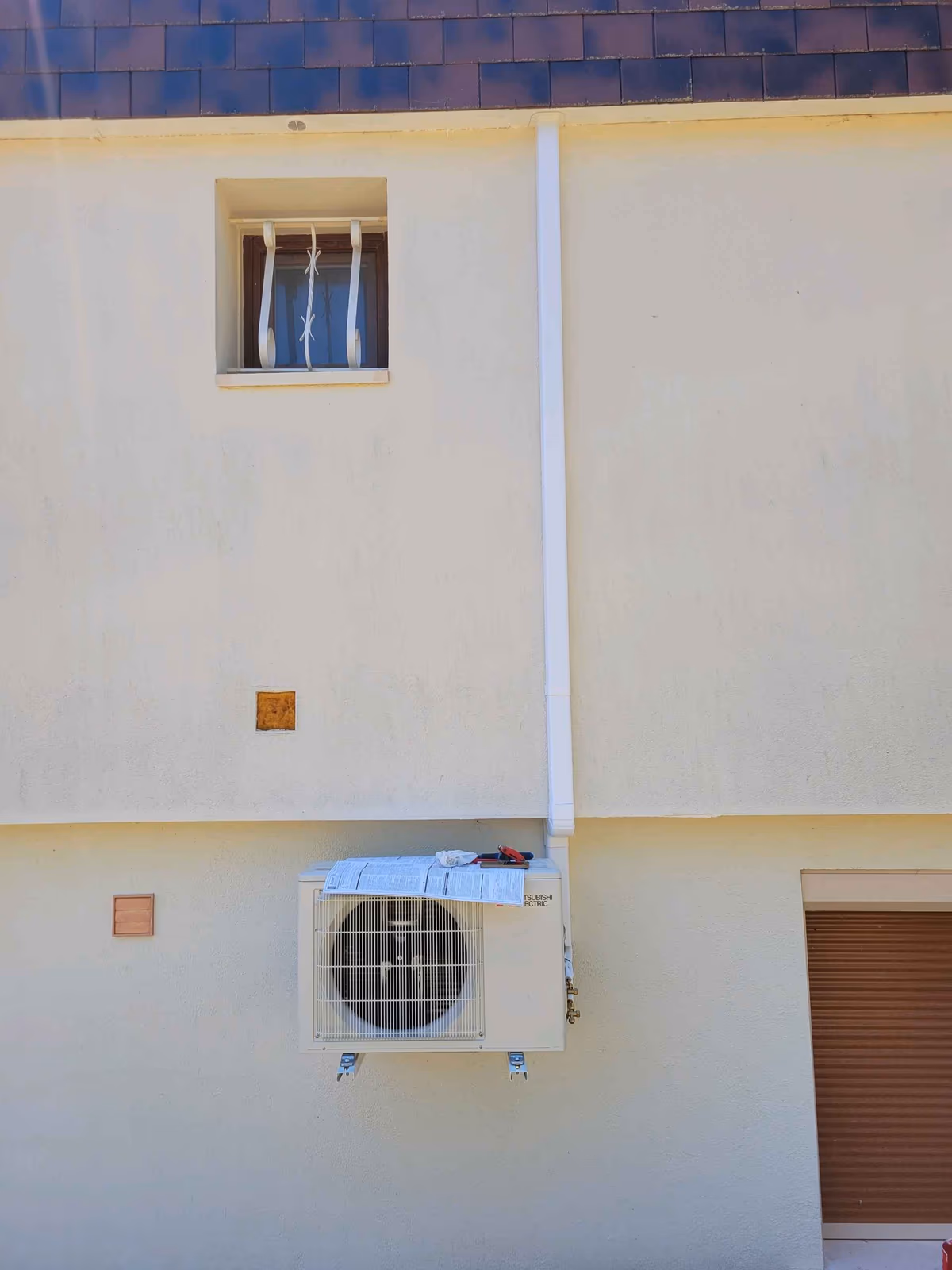 Unité extérieure de climatisation réversible Mitsubishi MSZ-HR50 installée par Kozéo à Marmagne, liaisons dissimulées en goulotte le long de la façade