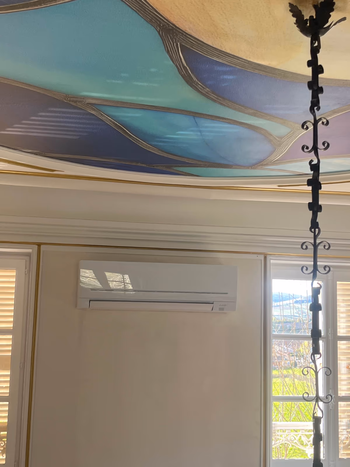 Unité murale de climatisation réversible Mitsubishi installée par Kozéo sous un plafond peint dans une demeure ancienne à Prissé